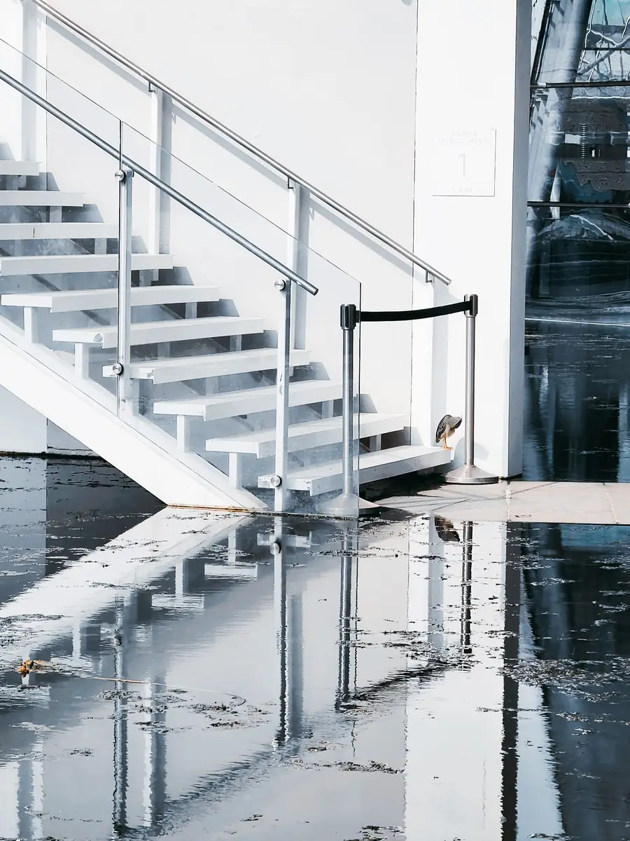 Standing water covering a hard floor at the bottom of a staircase
